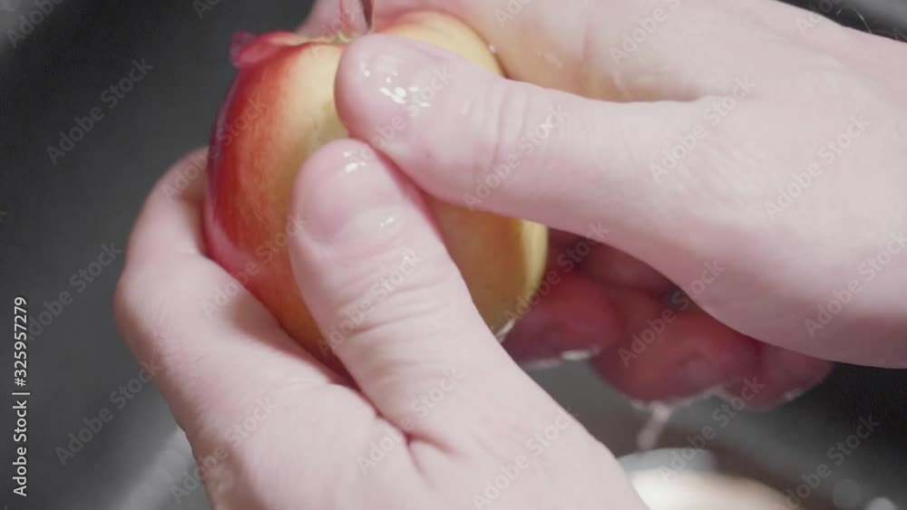 Man's hands hold apple under water and wash it carefully under running water. Turning off running water. Avoiding infections. Close up and slow motion view. Man's hands hold apple under water and wash it carefully under running water. Turning off running water. Avoiding infections. Close up and slow motion view.