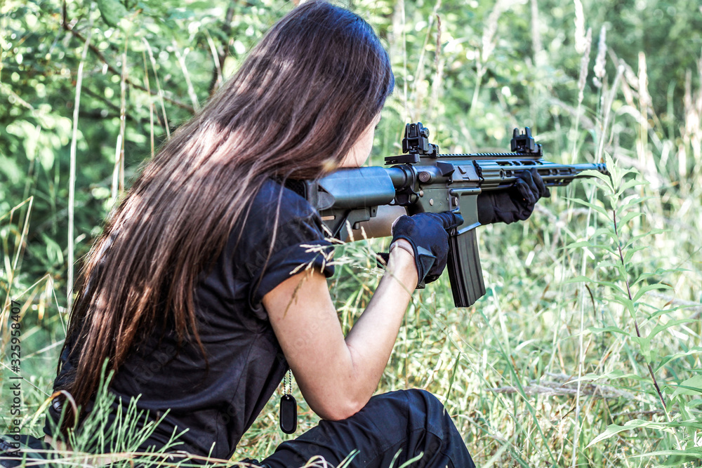 Fototapeta premium Girl in tactical clothes with a gun. Military woman. Black T-shirt and pants. Holster.SWAT