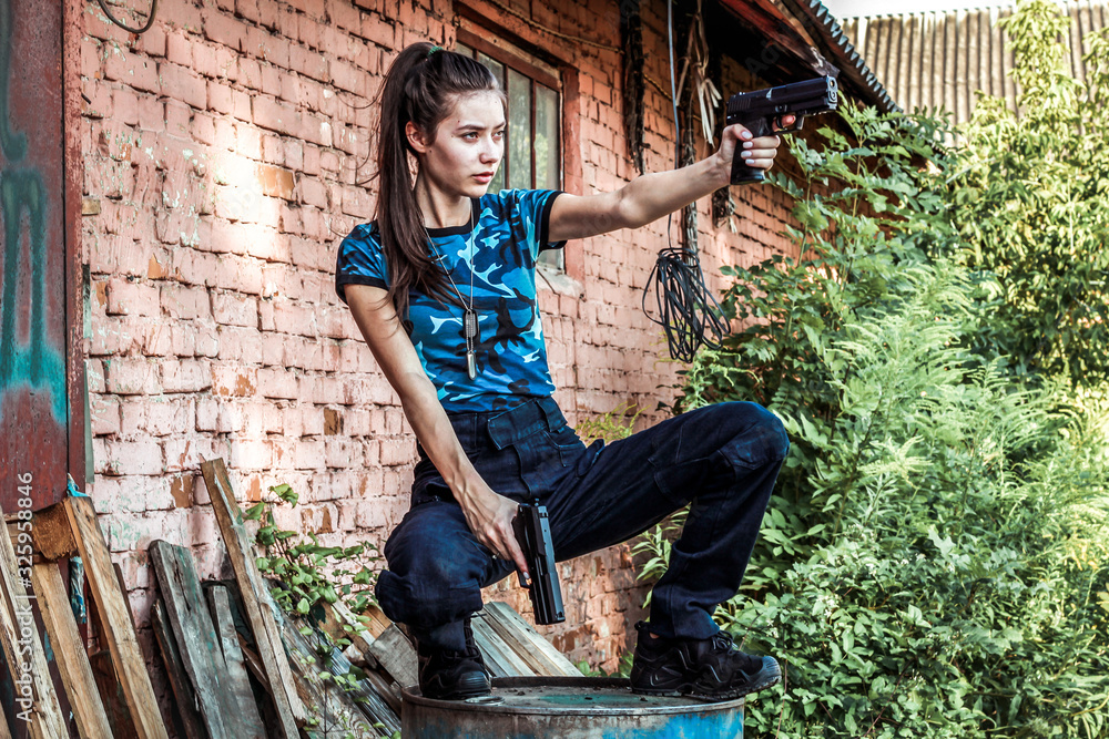 Girl in tactical clothes with a gun. Military woman. Blue camouflage T-shirt and bag with two pistols. Civilian clothing.