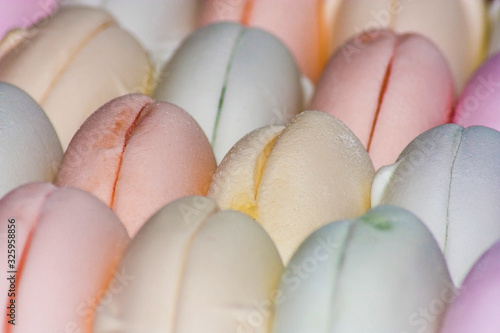 Fresh multicolored marshmallows lies in serried ranks in a box close up photo