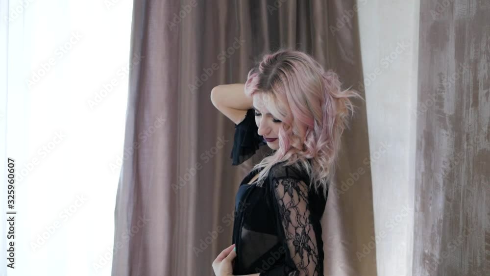 Young sexy blonde girl in black lingerie standing in bedroom near window and posing. Young sexy blonde girl in black lingerie standing in bedroom near window and posing.