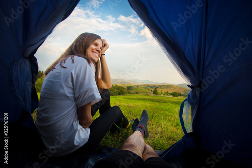 View from inside of tent. Man lying in tent and looking for his girlfriend. Hiking in mountains.