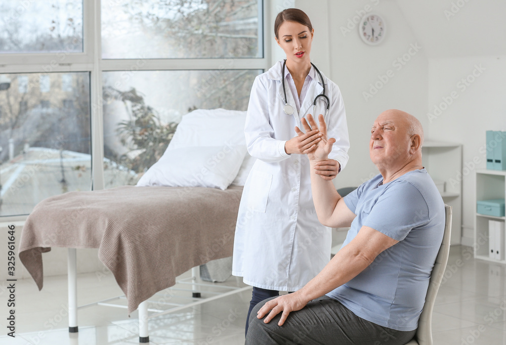 Obraz premium Female doctor working with senior man suffering from Parkinson syndrome in clinic