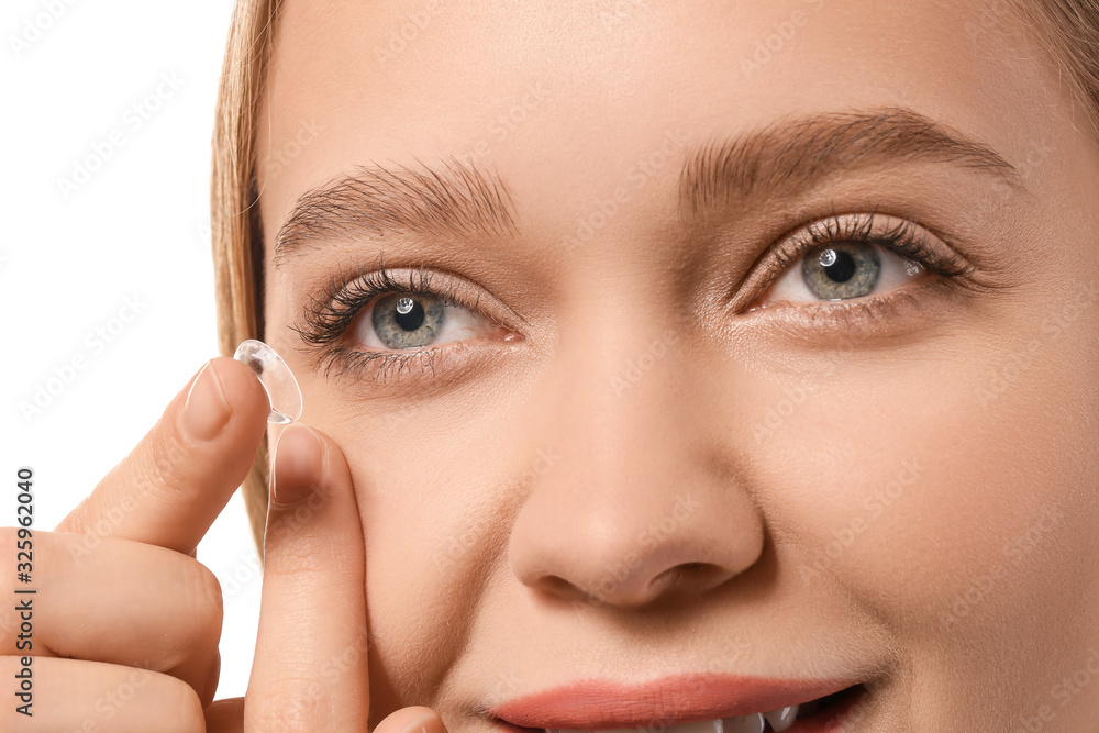 Young woman putting in contact lens on white background, closeup Young woman putting in contact lens on white background, closeup