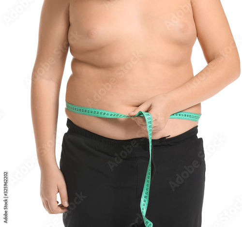 Overweight boy measuring his waist on white background