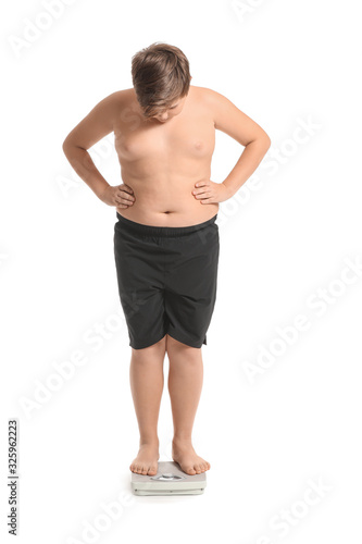 Overweight boy standing on scales against white background photo