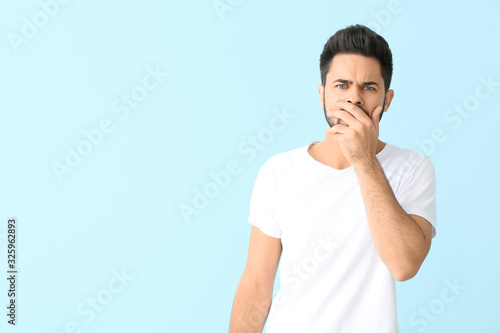 Portrait of worried young man on color background