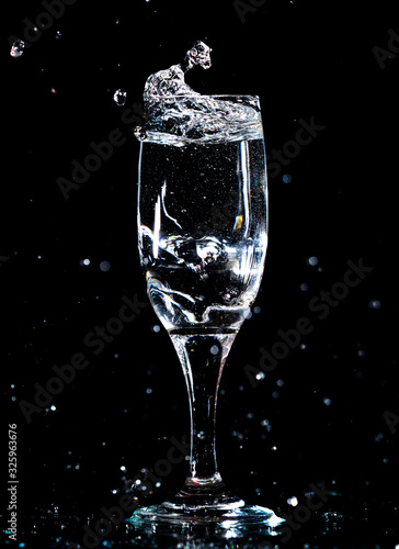 Water with splashes in a glass on a black background