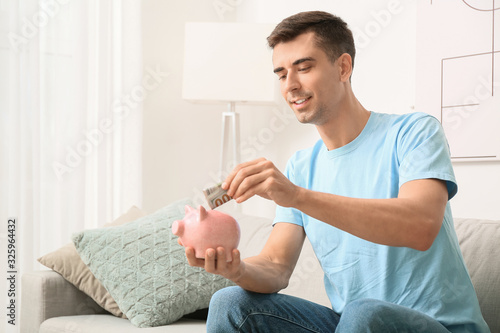Man putting money in piggy ...