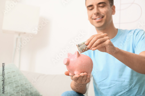 Man putting money in piggy ...
