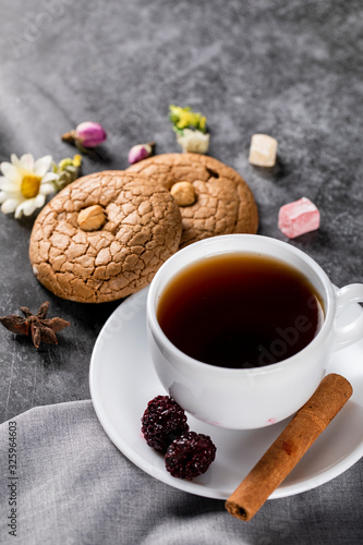 A cup of tea, almond cookies, berries, cinnamon and nuts