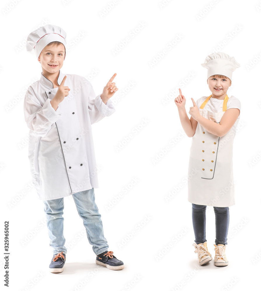 Cute little chefs pointing at something on white background Cute little chefs pointing at something on white background