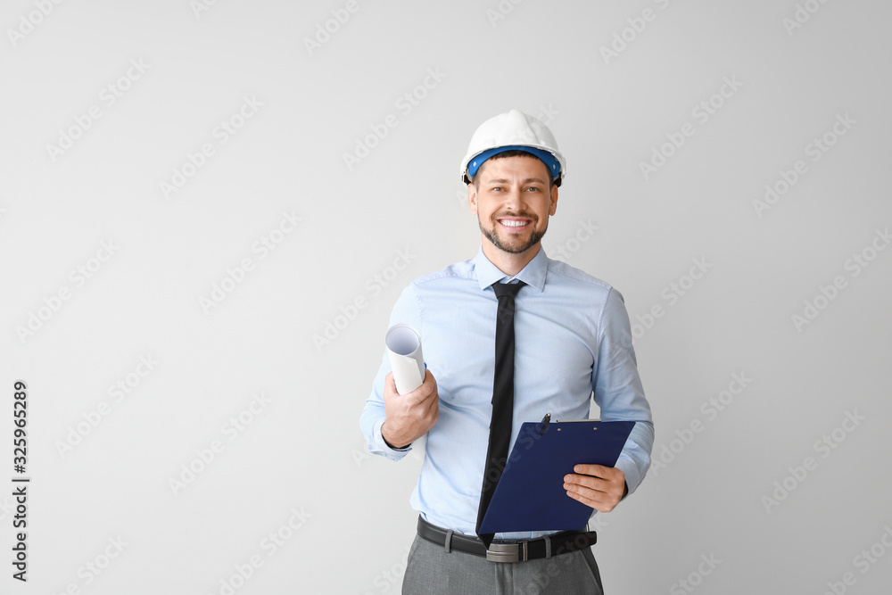 Male engineer with drawing on light background Male engineer with drawing on light background