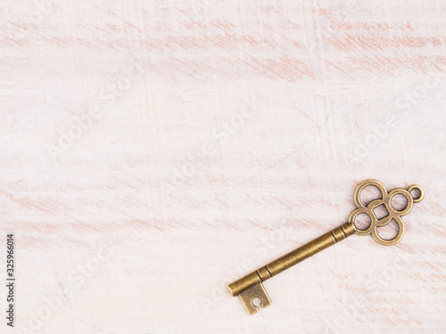 Old bronze key on light brown wooden background with copy space © zah108