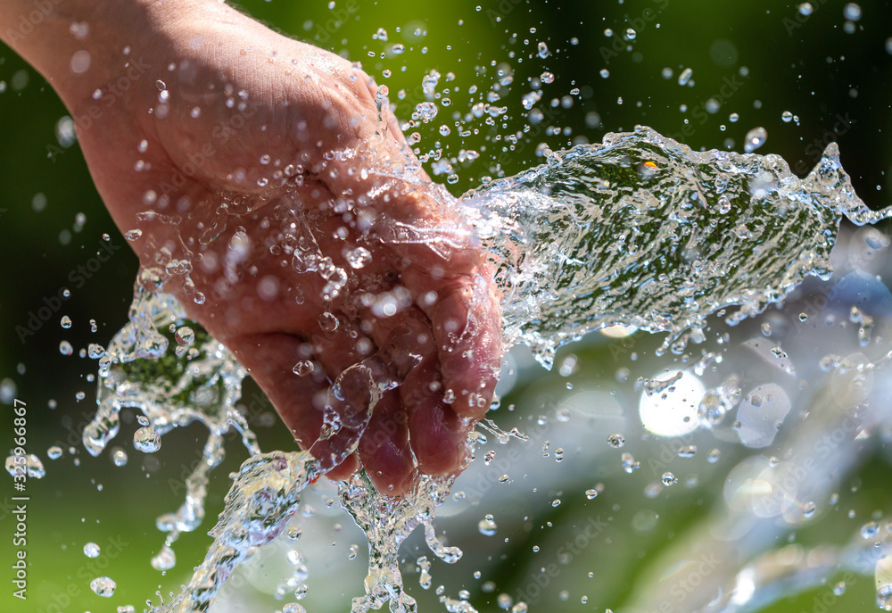 Fototapeta premium Hand of a man in the spray of water of the fountain