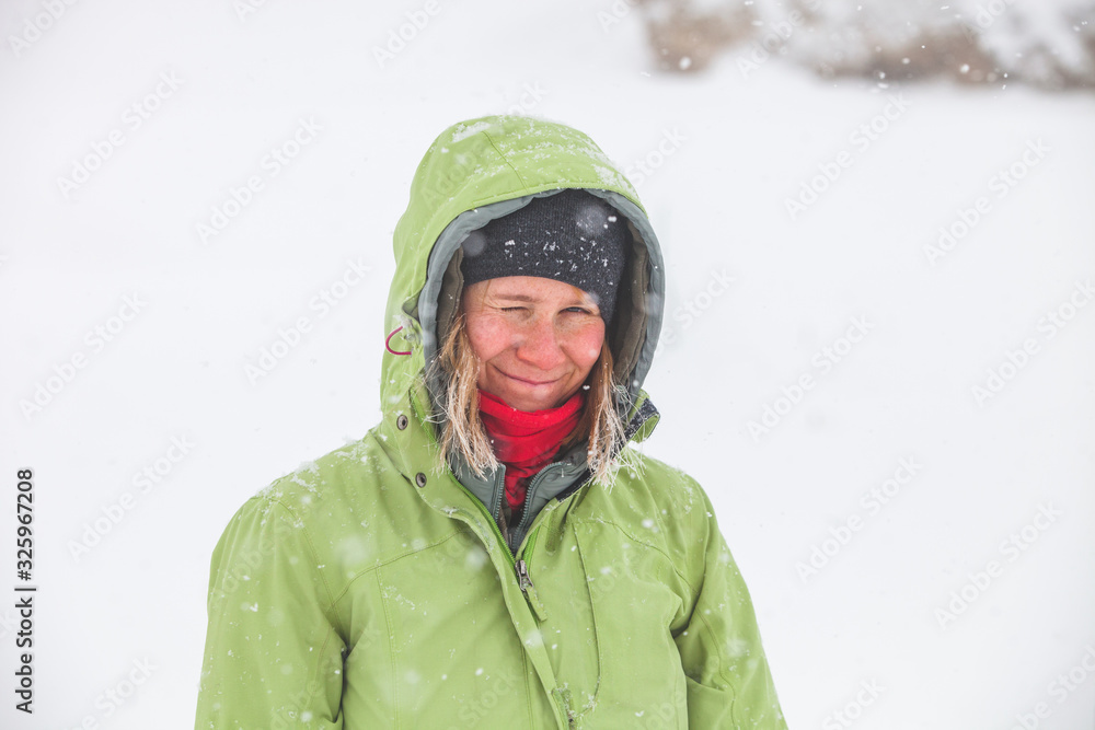 girl with hoarfrosted hair in green jacket grey hat and with red scarf in Caucasus mountains