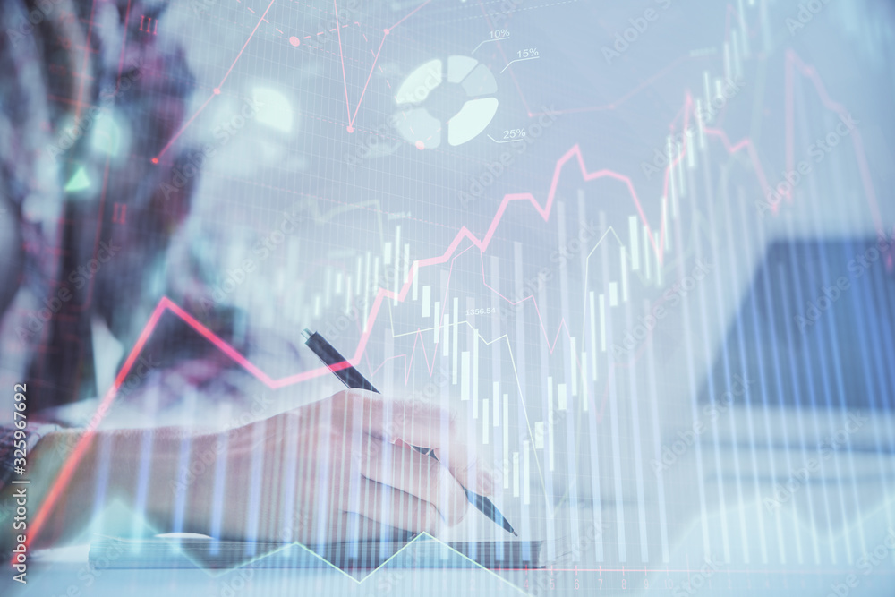 A woman hands writing information about stock market in notepad. Forex chart holograms in front. Concept of research. Double exposure A woman hands writing information about stock market in notepad. Forex chart holograms in front. Concept of research. Double exposure