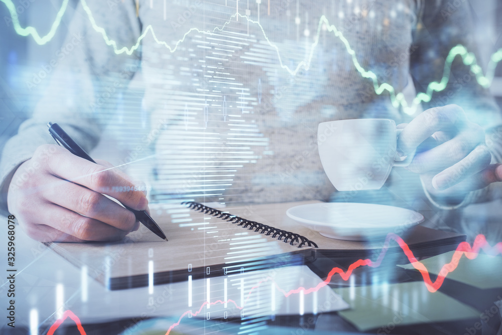 Forex chart hologram on hand taking notes background. Concept of analysis. Double exposure Forex chart hologram on hand taking notes background. Concept of analysis. Double exposure