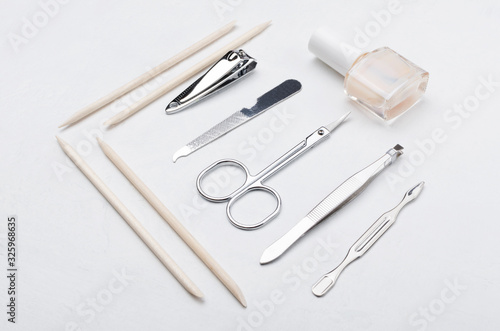 Orangewood sticks, nail polish, scissors, nail clipper, file on the white surface