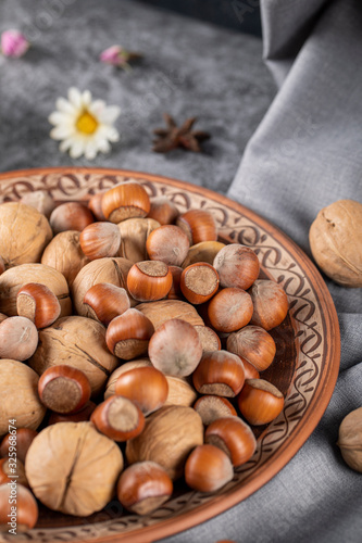 Nuts and walnuts in a pottery bowl and on the tablecloth with daisies around