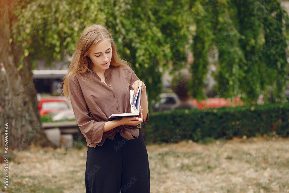 Beautiful girl studies. Student use the notebook. Lady in a summer park Beautiful girl studies. Student use the notebook. Lady in a summer park