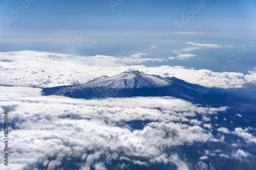 Etna volcano covered in snow. View from the plane through clouds