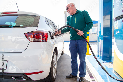 Older man filling up with gas in his eco-friendly car.