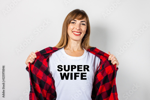 Young woman with a smile in a red shirt and white t-shirt on a white background. Super wife text has been added to the shirt. Concept for text, logo, shock, surprise. Banner