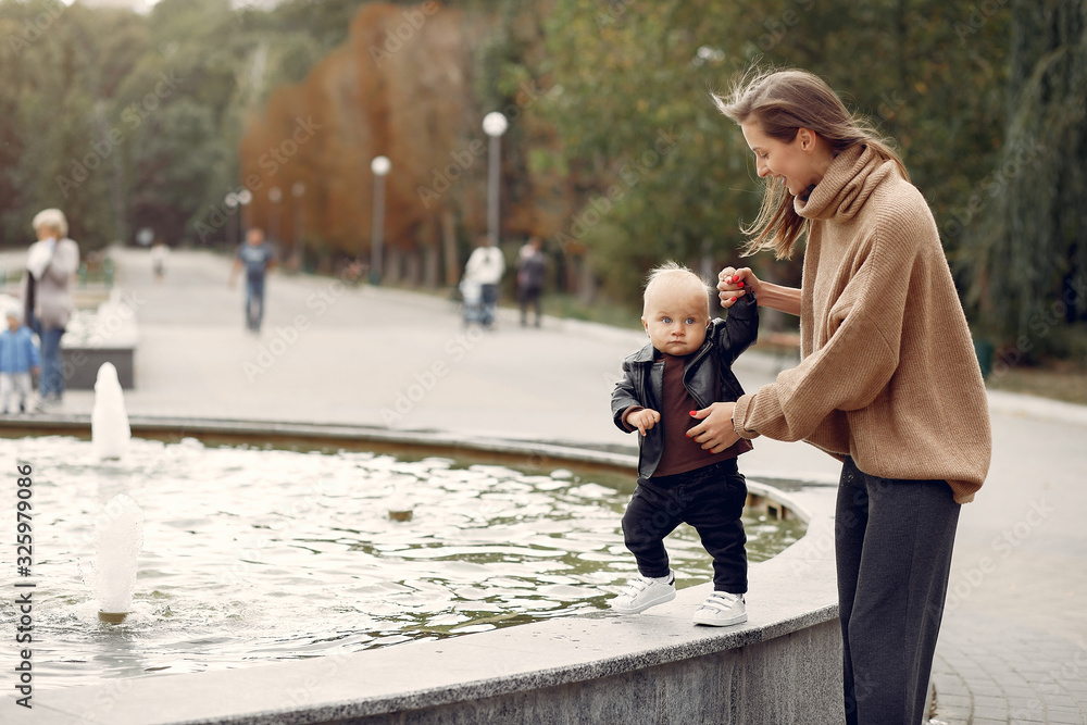 Fototapeta premium Family in a autumn park. Mother in a warm sweater. Cute little child