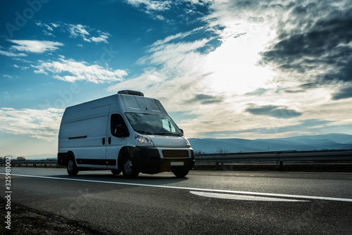 White van transporting through highway on bright sunny sunset.