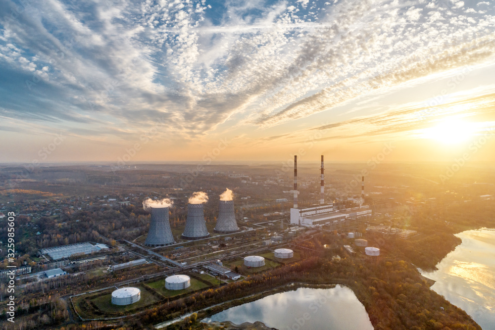 Obraz premium Power plant generating heat and electricity. High pipes and cooling towers are visible. Aerial view.