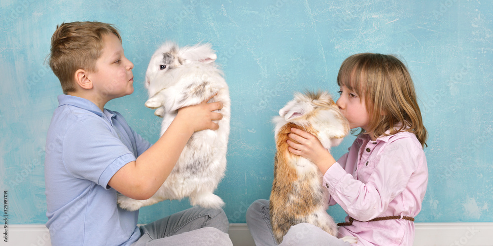 zwei Kinder geben ihren Hasen ein Küsschen zwei Kinder geben ihren Hasen ein Küsschen