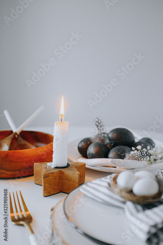 Easter table setting with white plate  gray textile napkin  candles  quail and chicken eggs and blossom branch.Mock up easter card