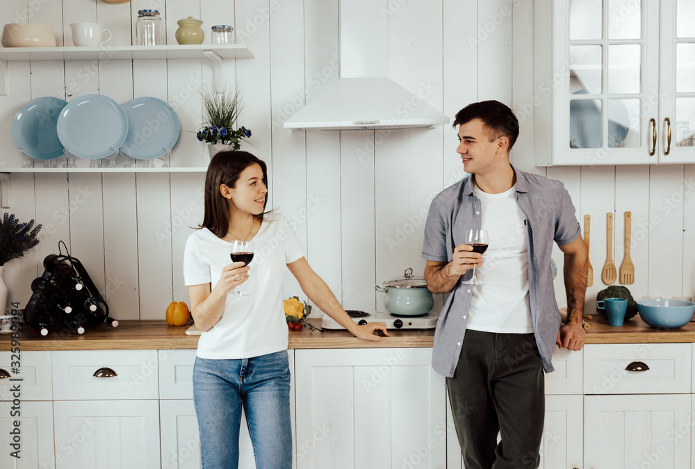 Young couple holding glasses with red wine in the kitchen Young couple holding glasses with red wine in the kitchen
