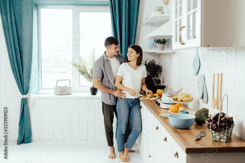 happy young couple have fun in modern kitchen indoor while preparing fresh fruits and vegetables food salad