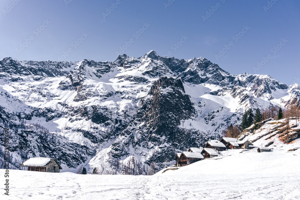 The traditional architecture of the Walser villages in the valleys of Monte Rosa, during a fantastic winter day, near the town of Alagna, Italy - February 2020.