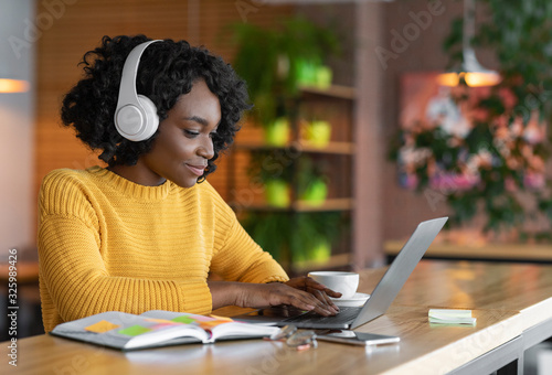 Young woman having online training, using laptop and wireless headset