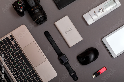 Flat lay of designer workplace. Top view work space photographer with digital camera, smartwatch, memory card, external harddisk, USB card reader and accessory on grey background with copy space.