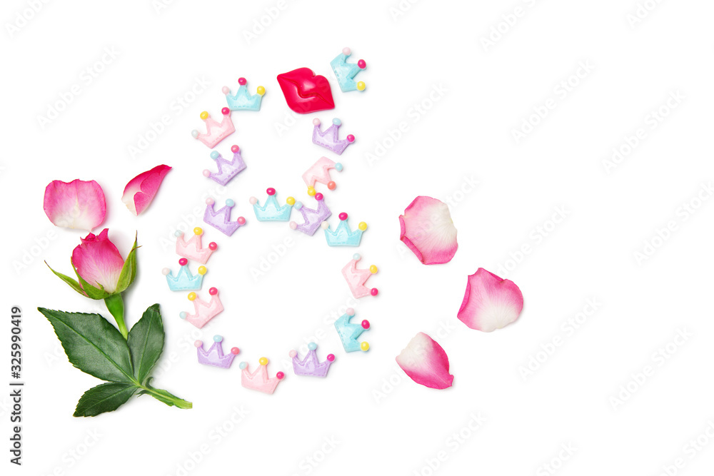Number 8 made from toy crowns and lips on a white isolated background. Rose bud and green leaves. Birthday card for a girl of 8 years. View from above. Number 8 made from toy crowns and lips on a white isolated background. Rose bud and green leaves. Birthday card for a girl of 8 years. View from above.