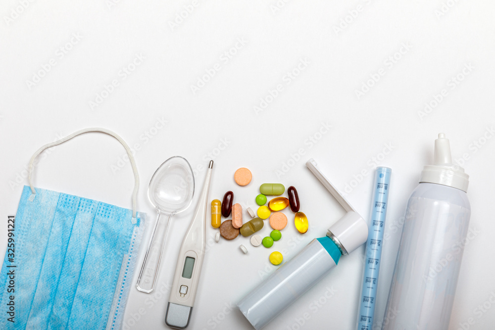 Treatment of colds and flu. Various medicines, a thermometer, sprays from a stuffy nose and a pain in a throat on a white background. Copy space for text. Medicine flat lay concept. Treatment of colds and flu. Various medicines, a thermometer, sprays from a stuffy nose and a pain in a throat on a white background. Copy space for text. Medicine flat lay concept.