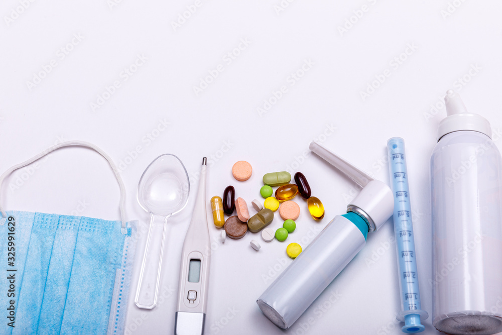 Treatment of colds and flu. Various medicines, a thermometer, sprays from a stuffy nose and a pain in a throat on a white background. Copy space for text. Medicine flat lay concept. Treatment of colds and flu. Various medicines, a thermometer, sprays from a stuffy nose and a pain in a throat on a white background. Copy space for text. Medicine flat lay concept.