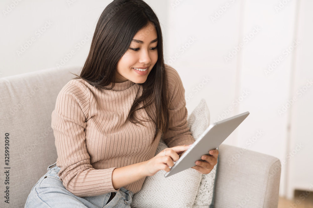 Interesting content. Asian girl reading blog on digital tablet Interesting content. Asian girl reading blog on digital tablet