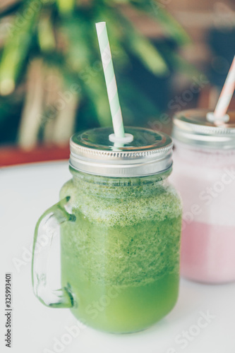 Healthy smoothie options in eco friendly glass jars with paper straws in a luxury gym recreation area or vegan cafe. Trendy muted toning, place for text