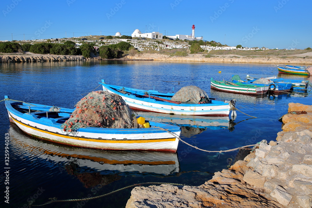 The old Fatimid port of Mahdia, Tunisia, with colorful fishing boats and the mosque lighthouse in the background