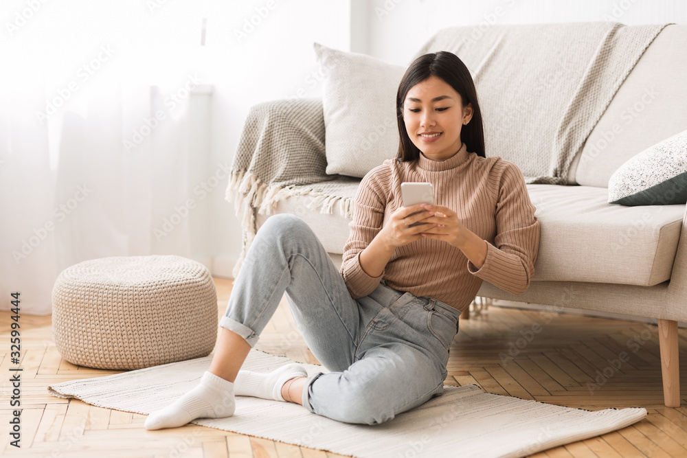 Modern girl checking emails on smartphone at home Modern girl checking emails on smartphone at home
