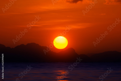 Fototapeta Naklejka Na Ścianę i Meble -  Big sun on sunset sky at the lake with silhouette mountain