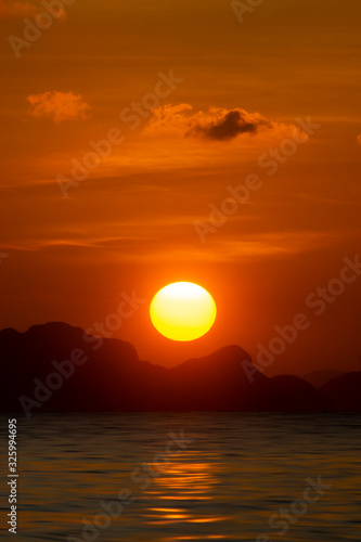 Big sun on sunset sky at the lake with silhouette mountain © noppharat