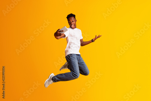 Handsome african guy making selfie while jumping