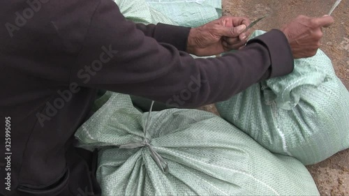  Volunteers closing filled with sand bags with string; Sand is used to build a sandbag dike for flood protection