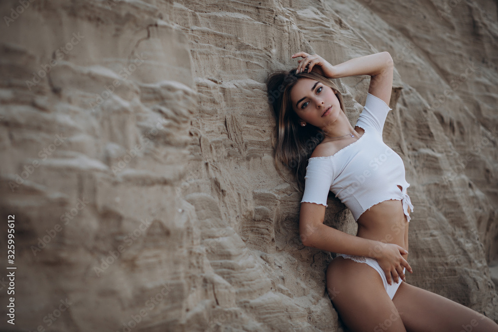 beautiful fair-haired girl in a white swimsuit on the beach. sunset beautiful fair-haired girl in a white swimsuit on the beach. sunset